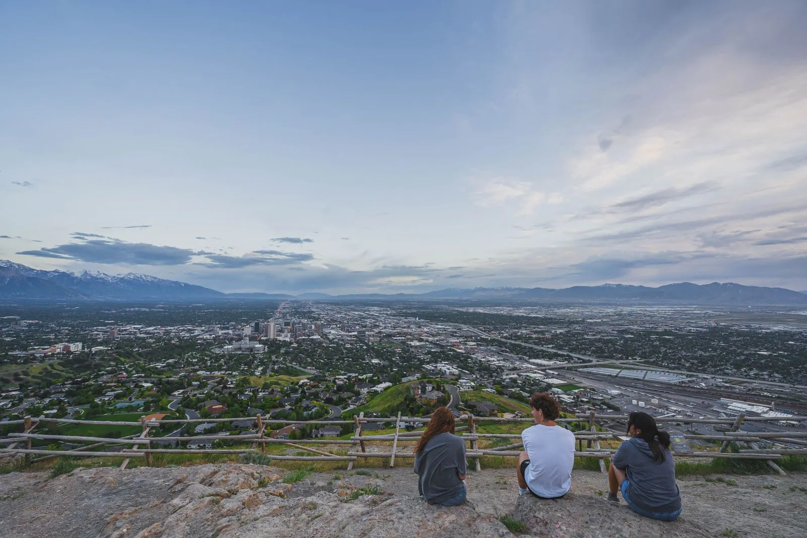 Group of friends sitting on a hill enjoying the panoramic cityscape view.